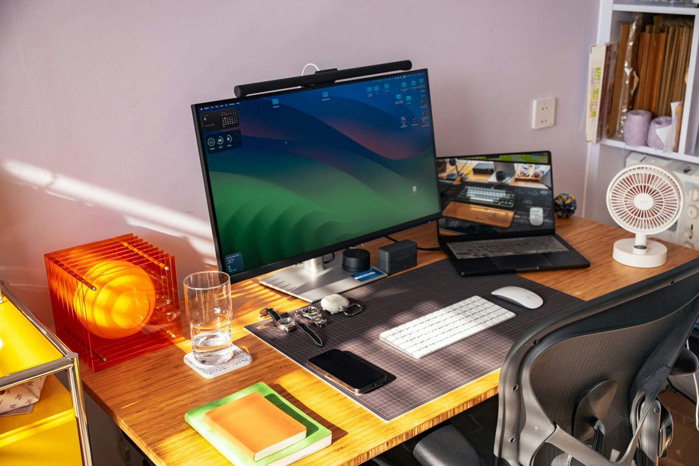 Ein Schreibtisch mit Bildschirm und Laptop in einem kleinen Büro