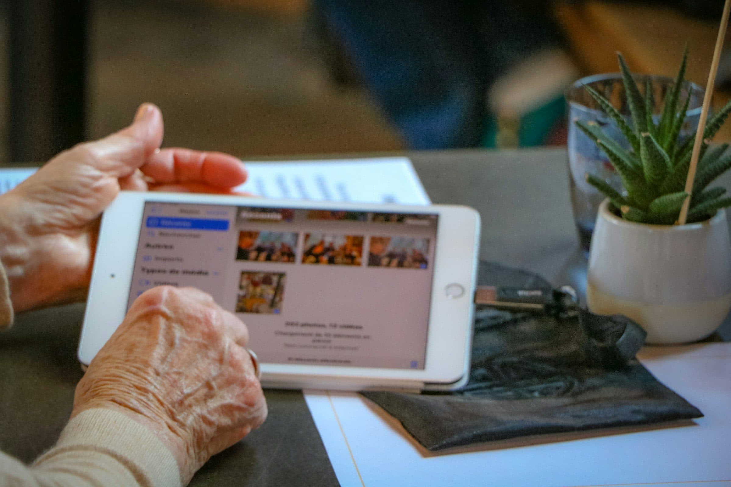 Die Hände einer älteren Person halten ein Tablet